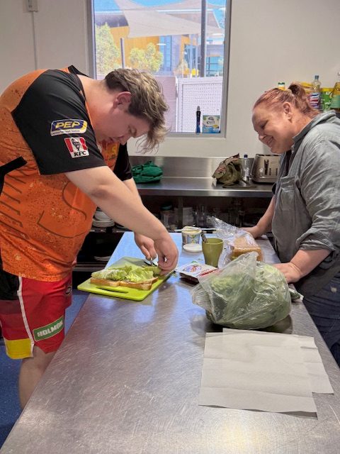 A teenager and a support worker cooking together