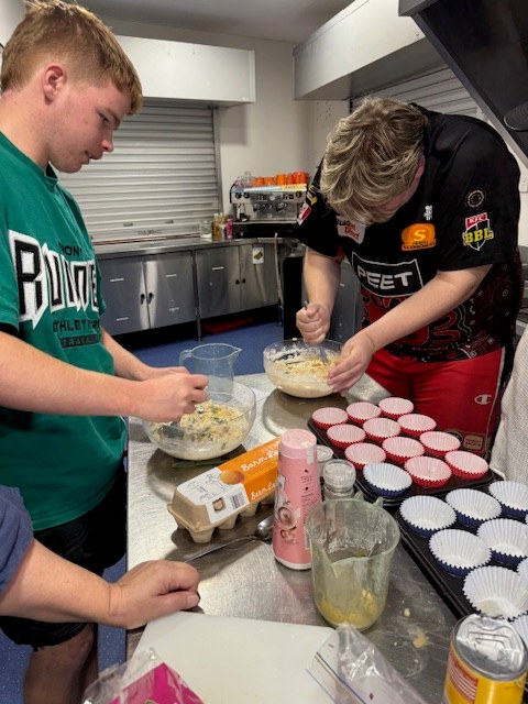 Two teenagers baking together in a community kitchen