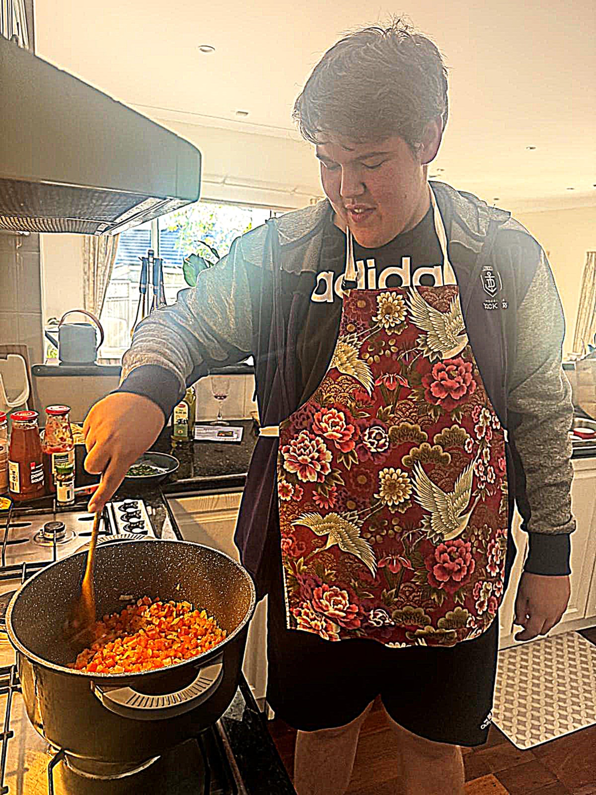 A teenager cooking a meal at the stovetop