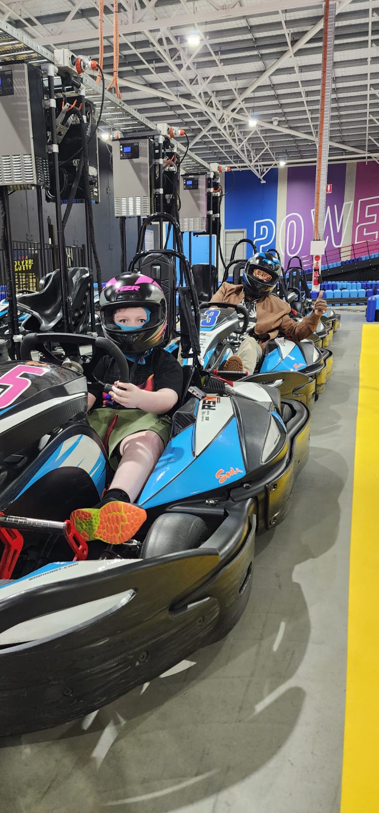 Two teenagers go-karting at an indoor track