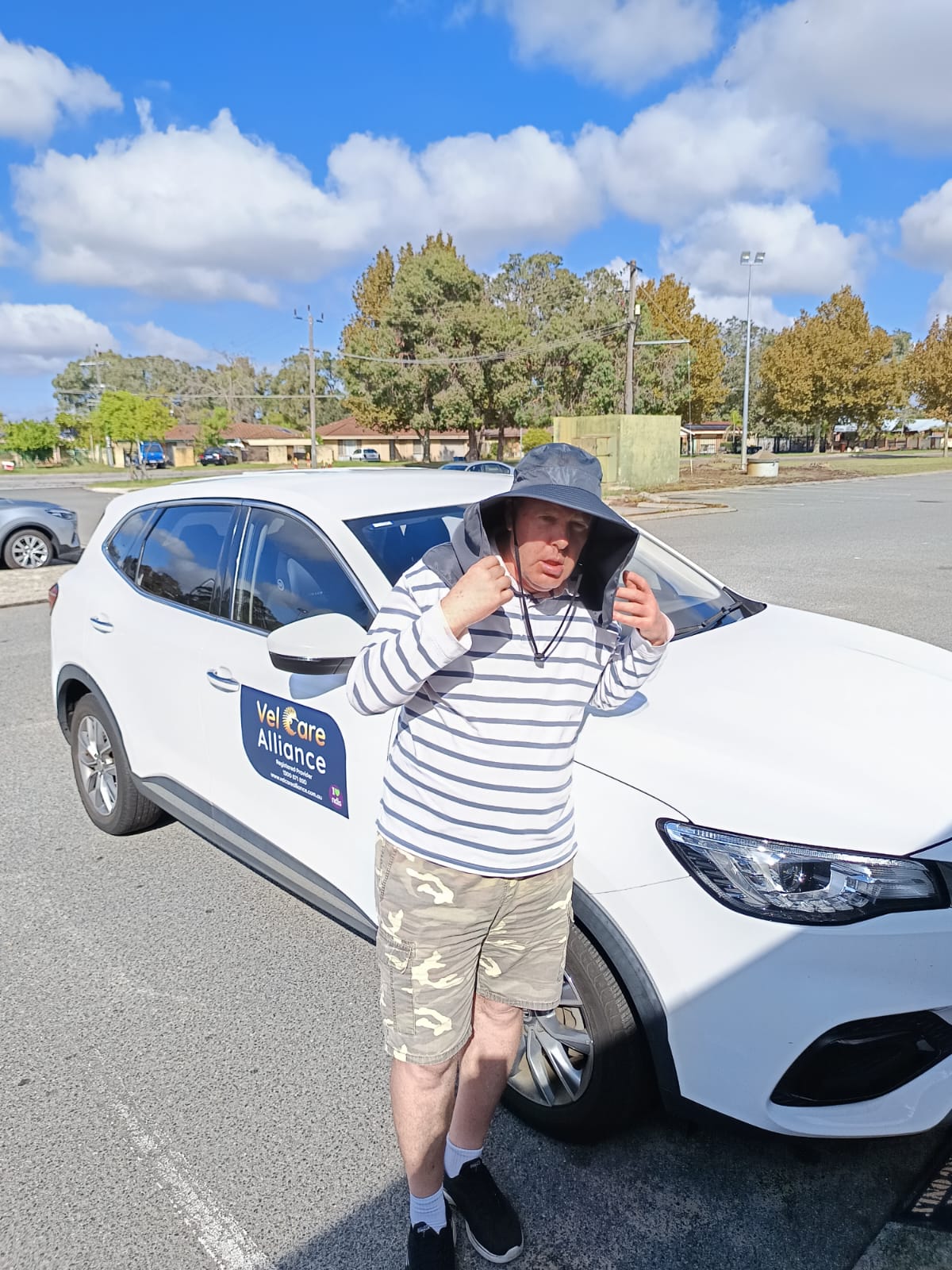 A teenager beside the Vel Care Alliance car